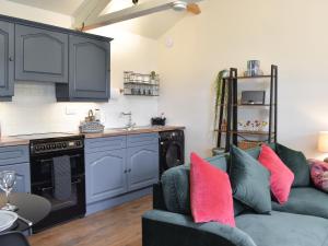 a living room with blue cabinets and pink pillows at The Owlery At Aysgarth in Aysgarth