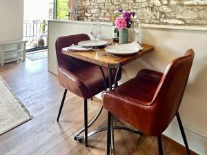 a table with two chairs and a table with wine glasses at The Owlery At Aysgarth in Aysgarth