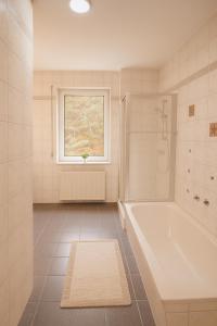 Un baño blanco con bañera y ventana. en SUNNYHOME Monteurwohnungen und Apartments in Bodenwöhr, en Bodenwöhr