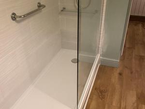 a shower with a glass door and a wooden floor at Seaspray in St Bees +20 photos