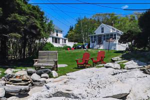 zwei rote Stühle und eine Bank in einem Hof in der Unterkunft Best View in ME in East Boothbay