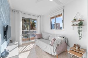 een witte woonkamer met een bank en een raam bij Pleamar 23 in Torrevieja