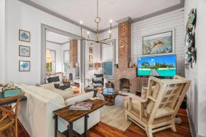 un salon avec un canapé blanc et une télévision dans l'établissement The White Pelican Inn-Trolley a 5 Minute Walk Stops at SeawallBeach, à Galveston