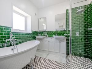 a green tiled bathroom with a tub and two sinks at Aird Cottage in Dunure
