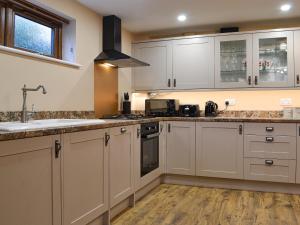a kitchen with white cabinets and a sink at The Old Forge in Burshill