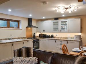 a kitchen with white cabinets and a leather couch at The Old Forge in Burshill