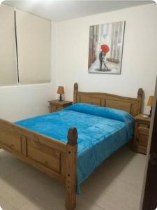 - une chambre avec un lit en bois et un couvre-lit bleu dans l'établissement Playa Blanca Beach and Lagoon Residences, à Cruce del Farallón