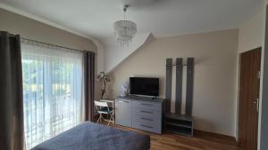 a bedroom with a bed and a dresser with a television at Olszynowy Gaj 4 in Liszki