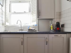 eine Küche mit weißen Schränken und einer Spüle und einem Fenster in der Unterkunft Wise Cottage in Keswick