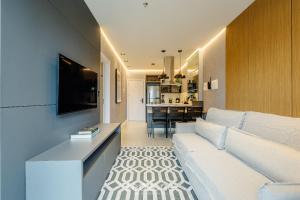 a living room with a white couch and a kitchen at Sua estadia exclusiva a poucos passos do Mar em Meia Praia - FFS in Perequê