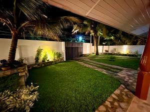 a backyard at night with a lawn and palm trees at Devon Surf . Inn - Hiriketiya in Dickwella