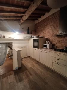 a kitchen with white cabinets and a brick wall at Emozioni Di Campagna in Palaia
