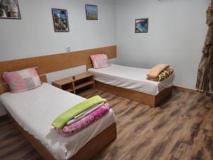 two beds in a room with wooden floors at Guest House Valchanovi in Elkhovo +36 photos