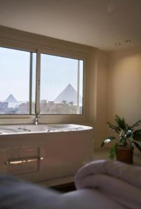 a bathroom with a tub and a window with a view at pYramids View in Cairo
