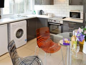 een keuken met een glazen tafel en een wasmachine bij Happys in St Ives
