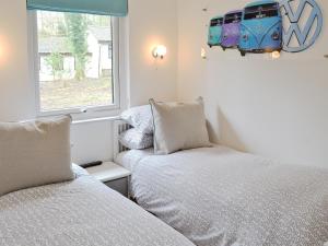 twee bedden in een kleine kamer met een raam bij Happys in St Ives