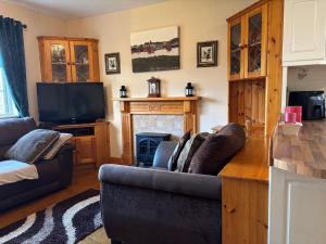 un salon avec un canapé et une télévision dans l'établissement Cottage 494 - Roundstone, à Roundstone