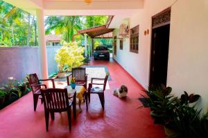 a patio with a table and chairs and a dog at Shasha House Bentota in Hettiwatta