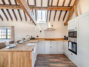 a kitchen with white cabinets and a wooden counter top at Corley Rocks Barn - Uk45939 in Corley