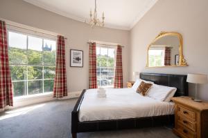 een slaapkamer met een bed, een spiegel en ramen bij Windsor Street Apartment in Edinburgh