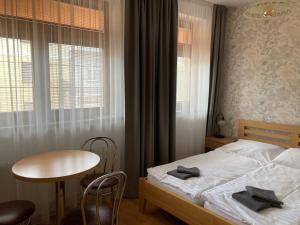 a bedroom with a bed and a table and window at Penzion U Radnice in Kyjov