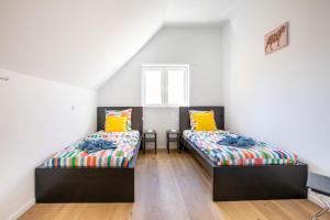 2 Betten in einem Zimmer mit weißen Wänden und Holzböden in der Unterkunft Maison 3 chambres avec terrasse côté champ in Illfurth