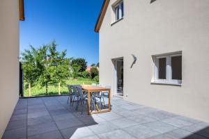 eine Terrasse mit einem Holztisch und Stühlen und einem Gebäude in der Unterkunft Maison 3 chambres avec terrasse côté champ in Illfurth