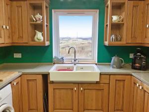 eine Küche mit Spüle und Fenster in der Unterkunft Laxdale Cottage in Leverburgh