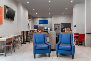 a waiting room with blue chairs and a bar at Holiday Inn Express & Suites Bronx - Zoo Area by IHG in Bronx
