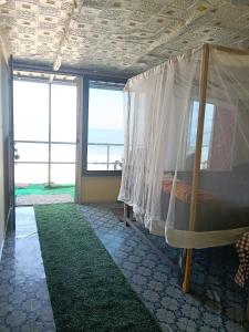 ein Schlafzimmer mit einem Himmelbett und einem grünen Teppich in der Unterkunft Nirvana Beach Cottages in Canacona