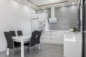 eine Küche mit einem weißen Tisch und schwarzen Stühlen in der Unterkunft Villa Infinity 1 in Chiclana de la Frontera