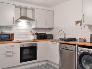 a kitchen with white cabinets and a sink and a dishwasher at Ransdale Cottage in Bridlington