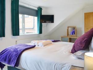 a bedroom with a large white bed with purple pillows at Ransdale Cottage in Bridlington