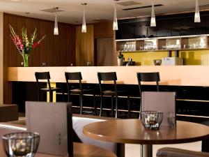 a restaurant with chairs and tables and a bar at Ferenc Hotel Budapest in Budapest