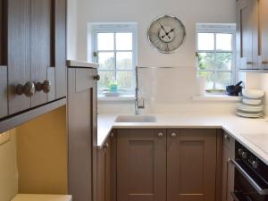 eine Küche mit Spüle und einer Uhr an der Wand in der Unterkunft Beach Comber Cottage in Marazion