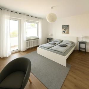 a bedroom with a bed and a chair and two windows at Köln Pulheim 48 in Pulheim