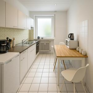 a kitchen with white cabinets and a table with a microwave at Köln Pulheim 48 in Pulheim