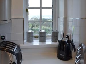 eine Küchentheke mit drei Kaffeetassen auf einem Fensterbrett in der Unterkunft Beach Comber Cottage in Marazion