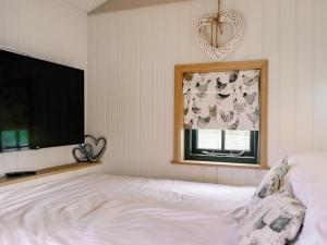 een slaapkamer met een bed, een tv en een raam bij Poppie's Shepherd Hut - Uk50227 in Redmile +19 foto's
