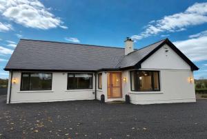a white house with a black roof at Willow Lodge Cashel- Rock View-Sleeps 8 guests-Spacious- Cosy in Cashel