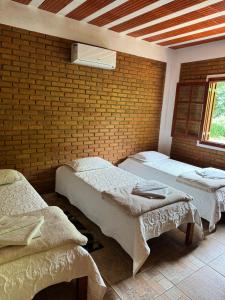 ein Zimmer mit zwei Betten und einer Ziegelwand in der Unterkunft Hotel Fazenda Bavária in São Lourenço
