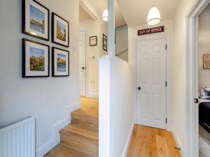 a hallway with a white door and some pictures on the wall at The Colleys in Lechlade