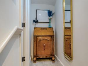 a wooden cabinet in a hallway next to a mirror at The Colleys in Lechlade