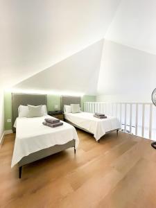 two beds in a room with white walls and wooden floors at B-Rent Oasis Emma's Suite - 5 People in Corralejo