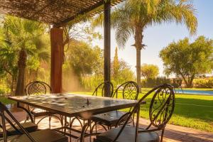 a table and chairs on a patio with palm trees at Luxury Villa - Pool Atlas Views & Wakeboard Lake in Marrakech