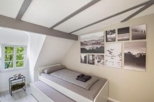 une chambre blanche avec un lit et des photos sur le mur dans l'établissement Am Röntgenmuseum, à Blume
