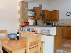 een keuken met een houten tafel en een fles wijn bij Riccal Heads in Lastingham