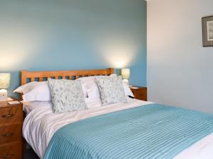 een slaapkamer met een bed en een blauwe muur bij Almond Cottage in Holker