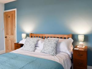 een slaapkamer met een bed met blauwe muren en 2 lampen bij Almond Cottage in Holker +7 foto's