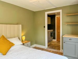 a bedroom with a white bed and a kitchen at Studio On The Green - Uk48298 in Chinley +2 photos